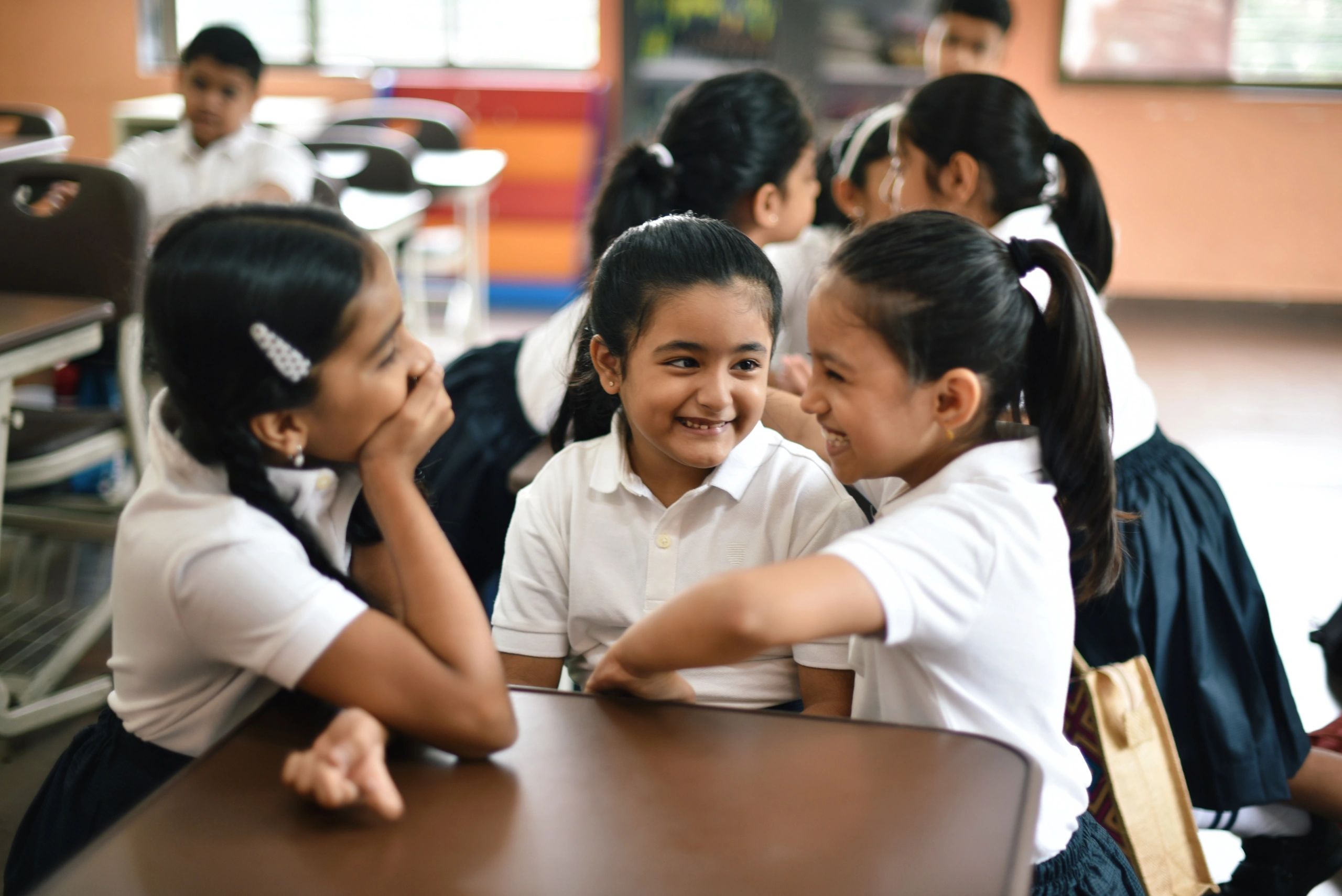 School girls talking in groups in a classroom during break
